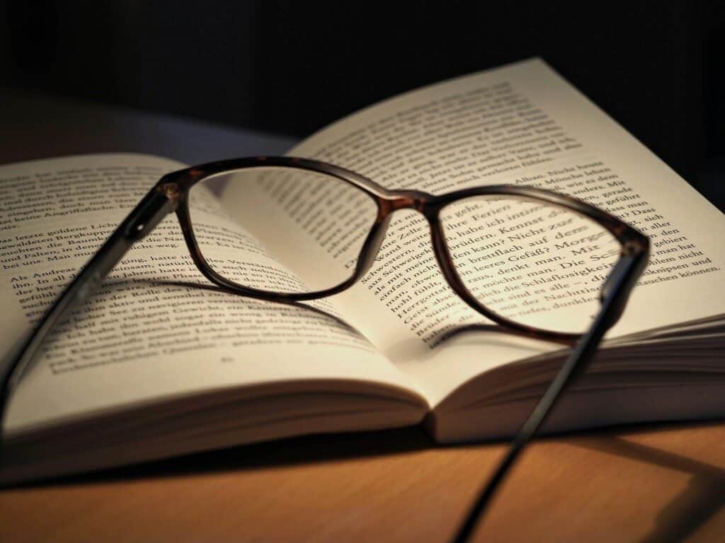 Photo montrant un livre ouvert sur lequel est posée une paire de lunette, pour représenter l'étude, la mémorisation, la compréhension.